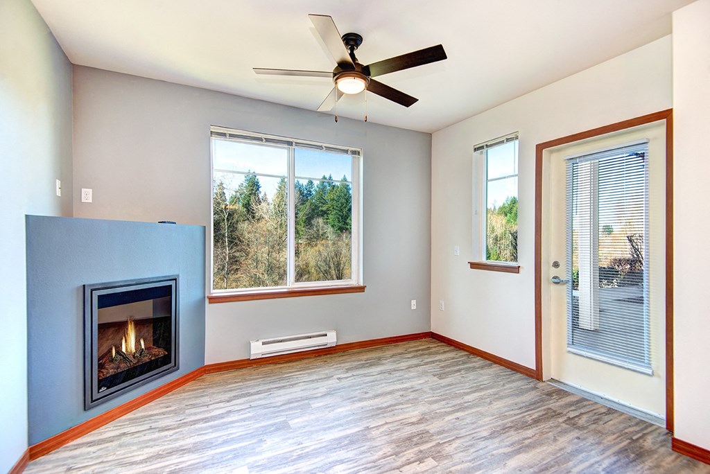 an empty living room with a fireplace and a ceiling fan