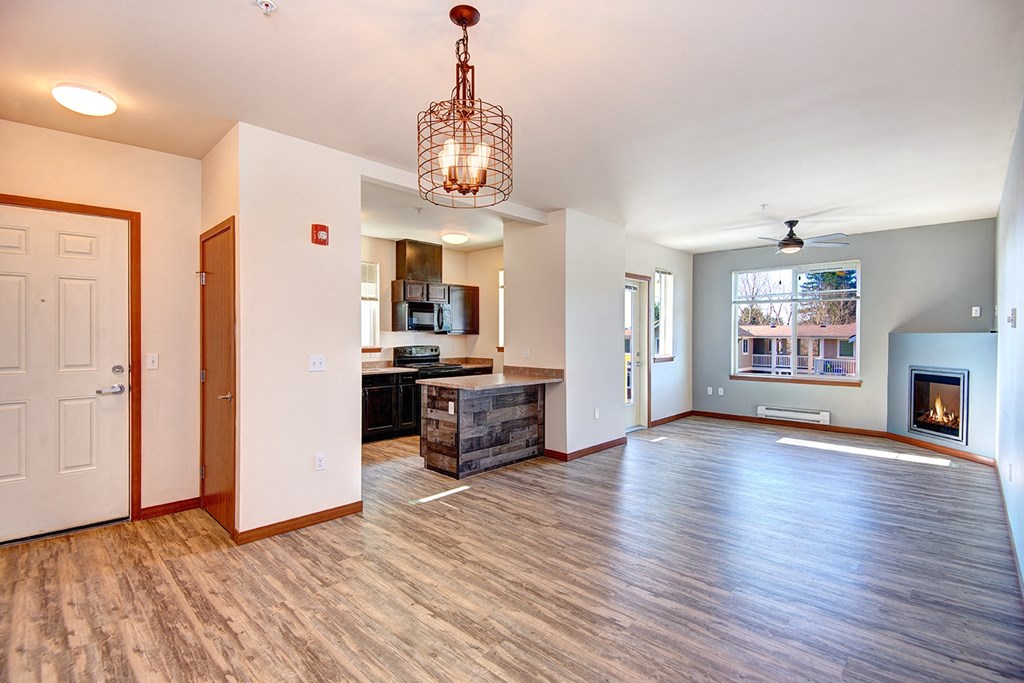 an empty living room with a fireplace and a kitchen