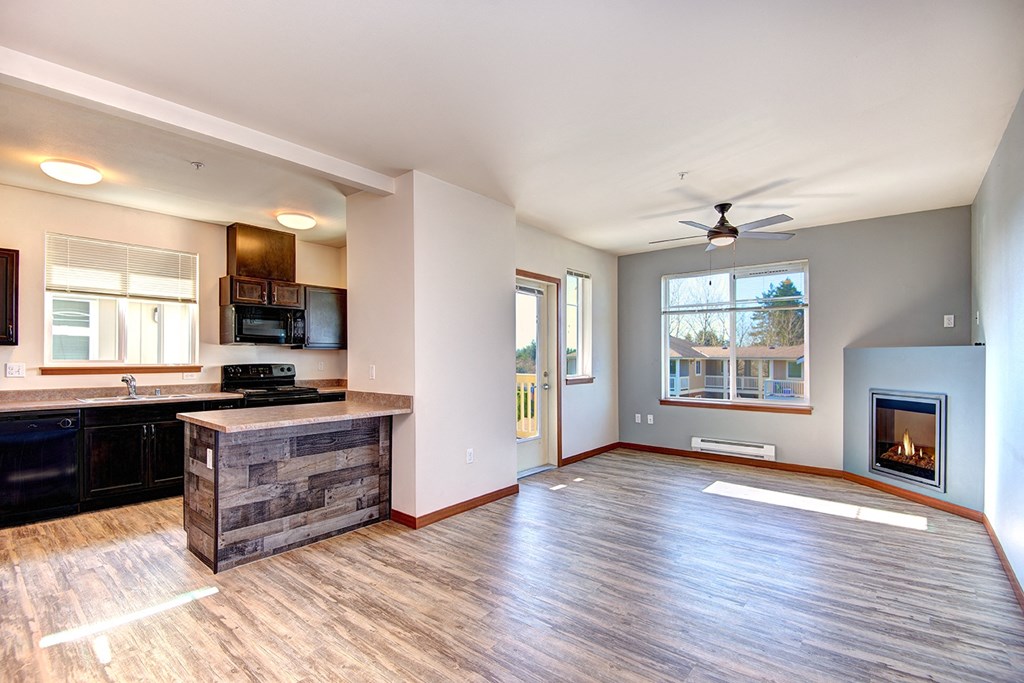 an empty living room with a fireplace and a kitchen