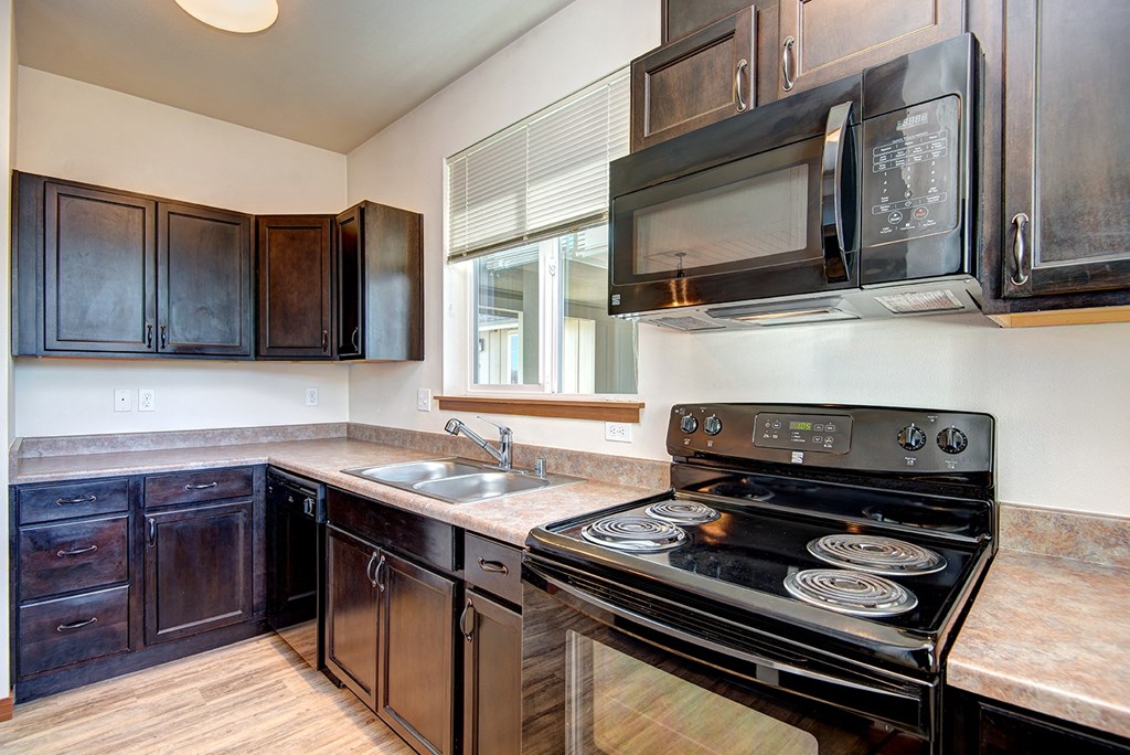 an empty kitchen with black appliances and wooden cabinets