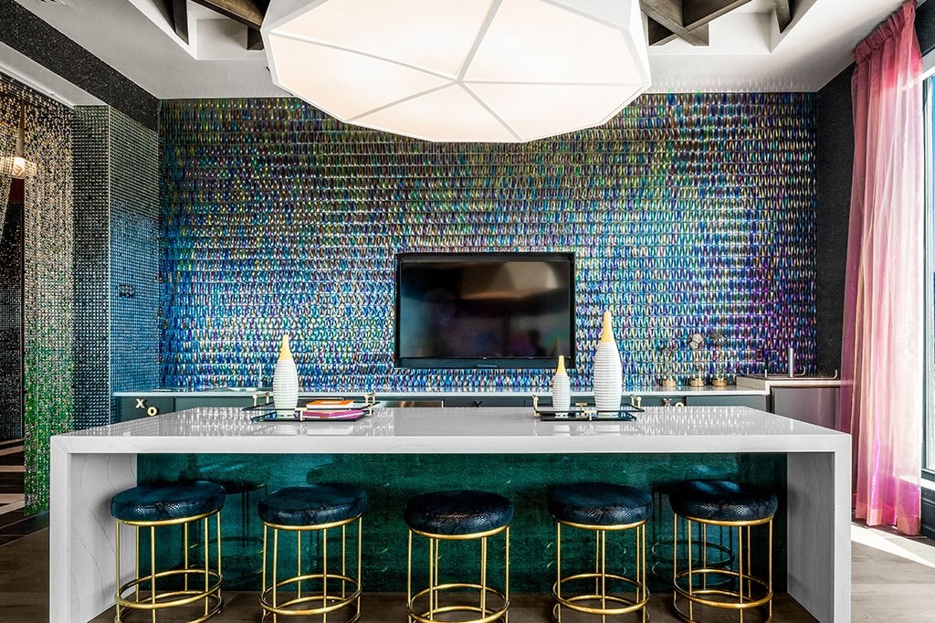 a bar with stools and a television in a room with colorful tiles