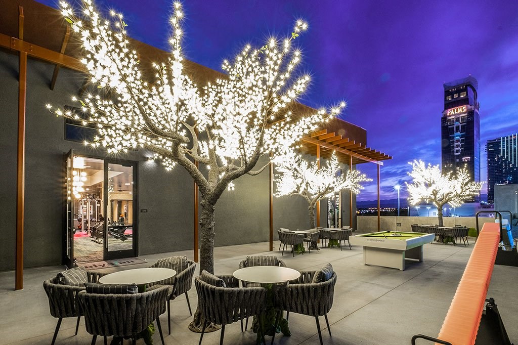 a patio with tables and chairs and a tree with lights