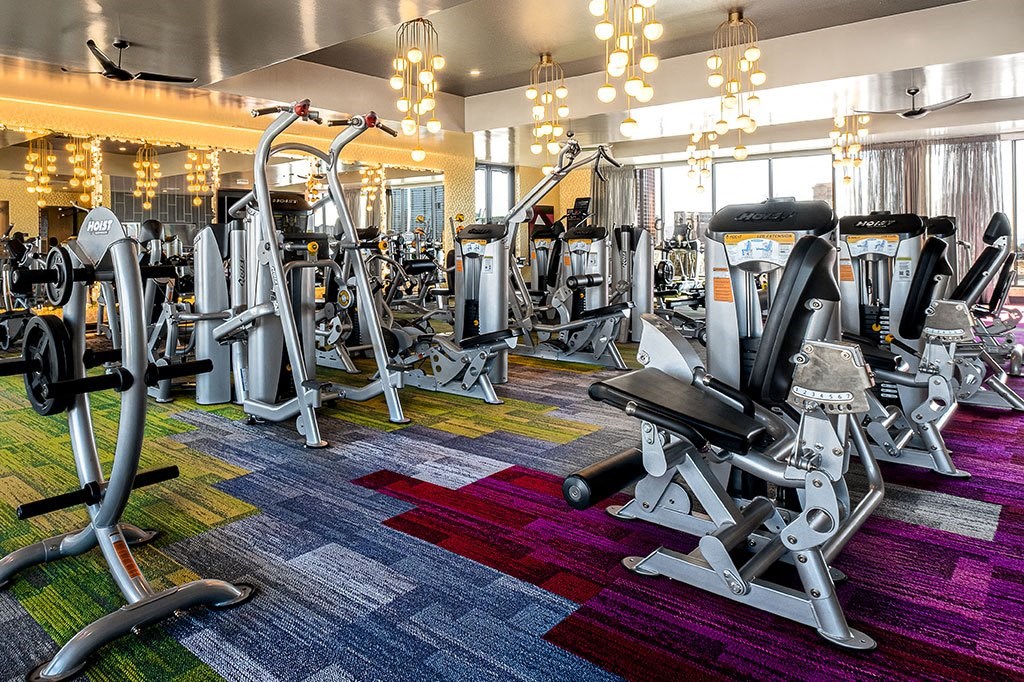 a gym with various cardio machines and weights on a colorful rug