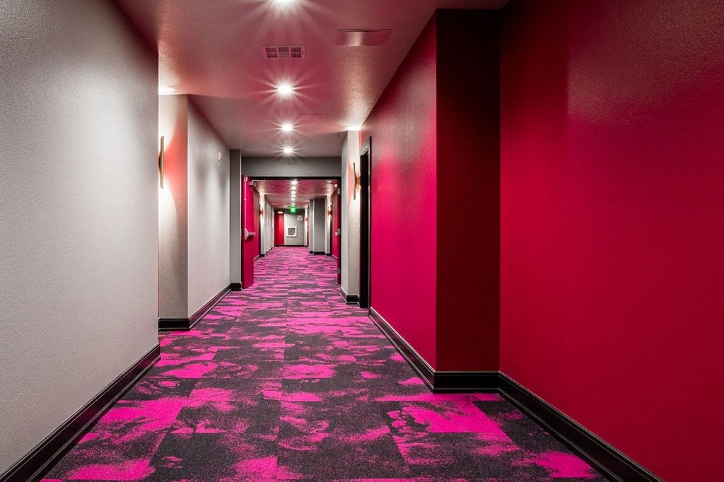 a long hallway with red walls and pink carpeting