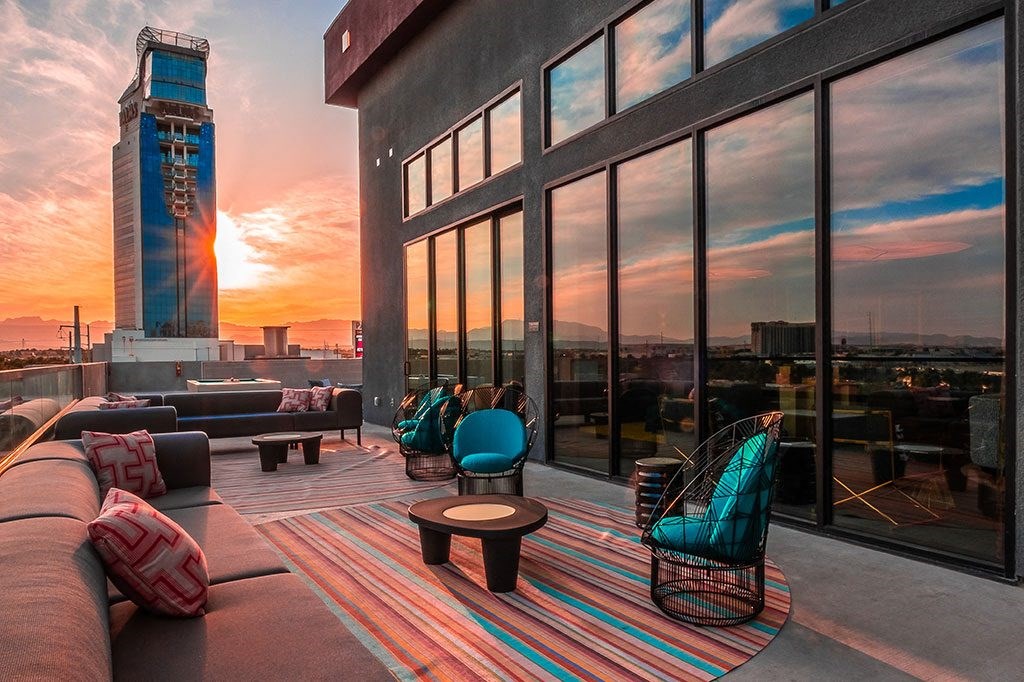 a rooftop lounge with a view of a skyscraper and a sunset