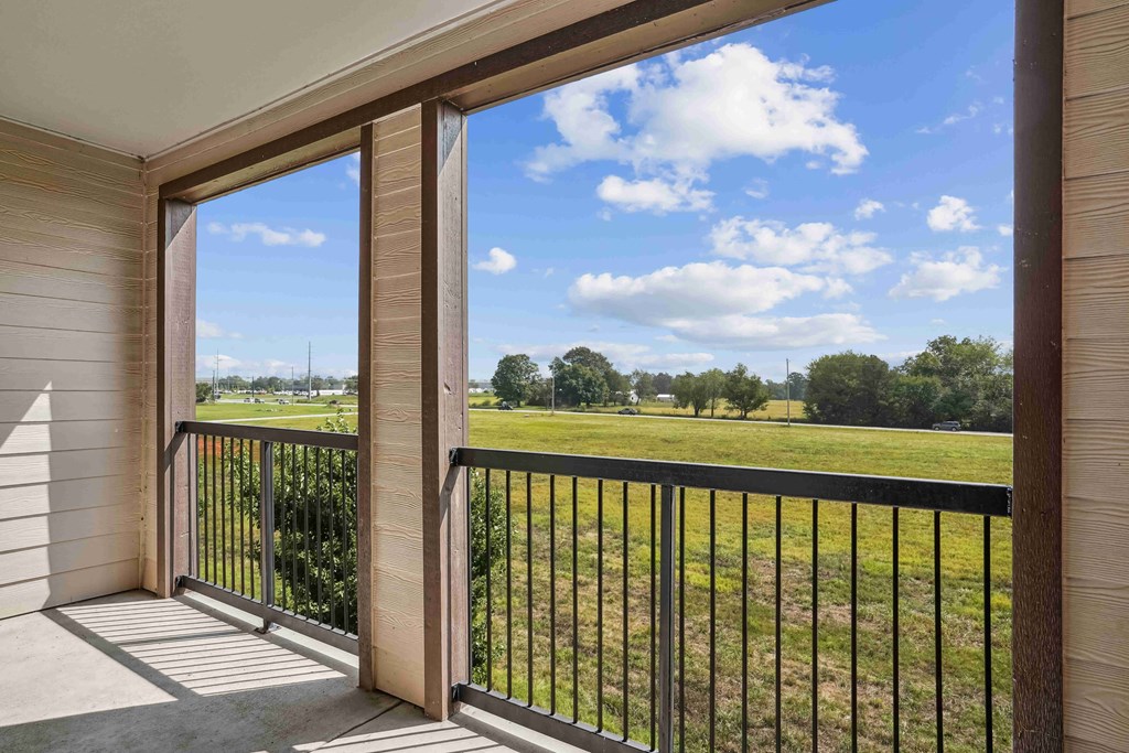 Apartments for Rent in Bentonville, AR 72713– Parc at Bentonville -   A balcony with a view of a grassy field and trees.