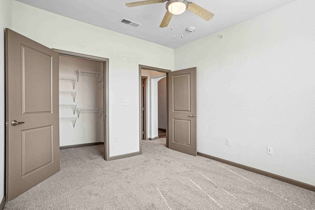 A room with a ceiling fan and carpeted floor.