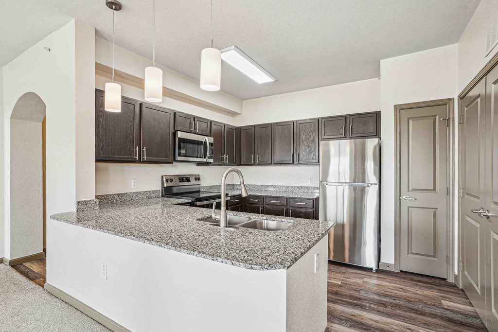 1 & 2-Bedroom Apartments for Rent in Bentonville, AR – Parc at Bentonville – A kitchen with a granite countertop and stainless steel appliances.