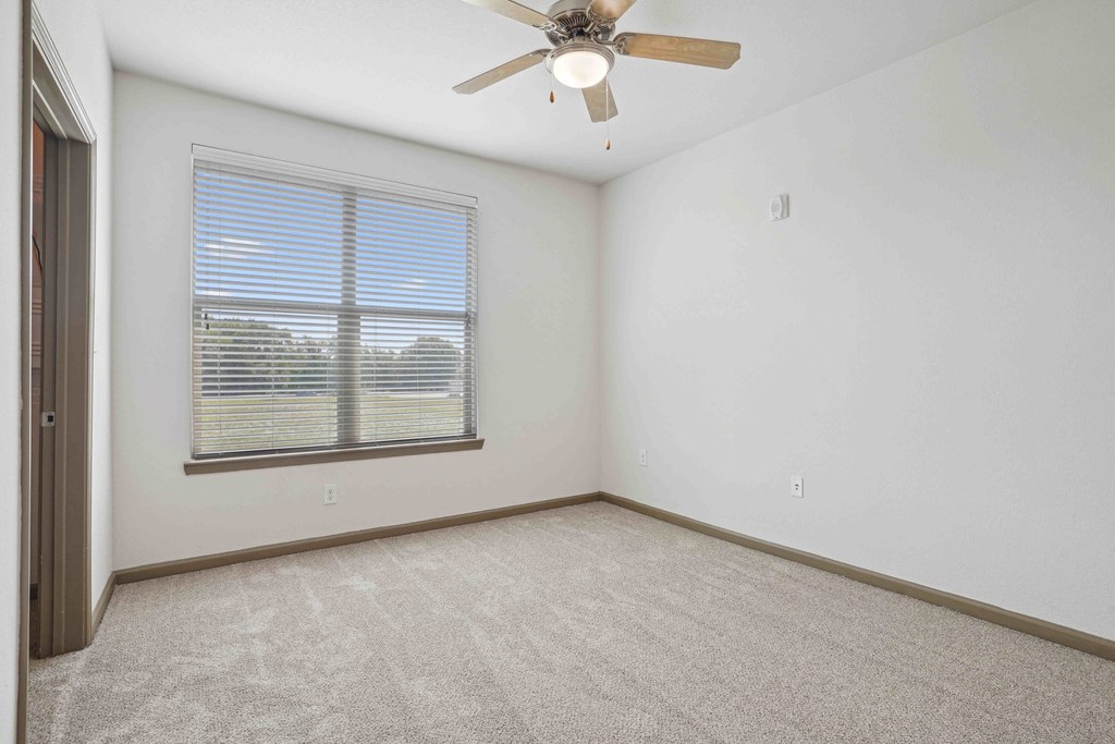 1 & 2-Bedroom Apartments for Rent in Bentonville, AR – Parc at Bentonville – A room with a ceiling fan and a window with blinds.