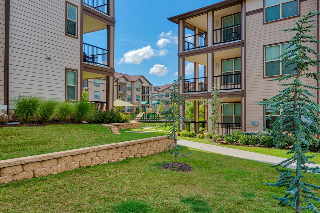 Pet-Friendly Rentals in Bentonville, AR – Parc at Bentonville – Exterior photo with trees and grass and building