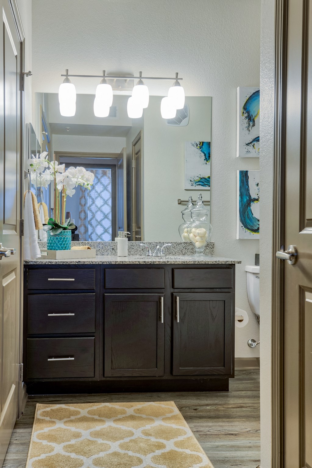This is the bathroom with a single sink and mirror and lighting and cabinets