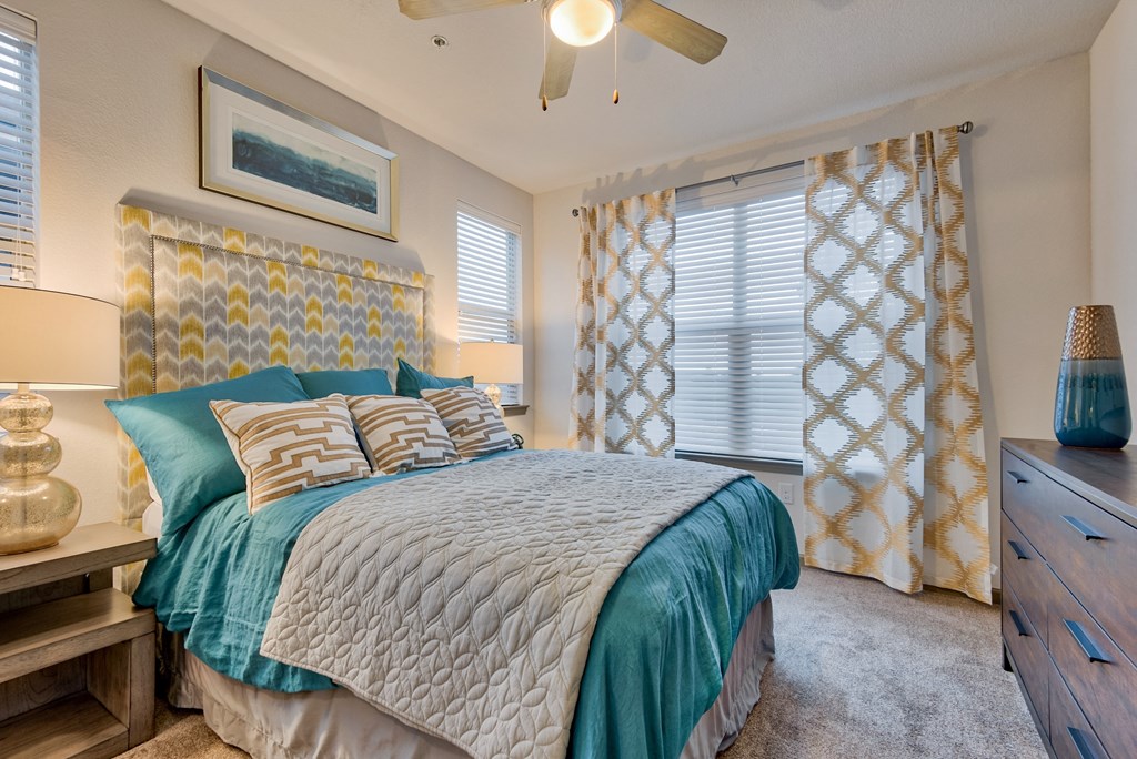 bedroom with the bed and dresser and night stand and window and ceiling fan at Parc at Bentonville Apartments in Bentonville, AR