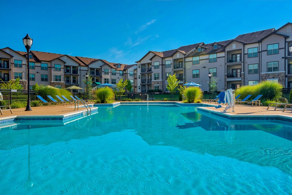 1 & 2-Bedroom Apartments for Rent in Bentonville, AR – Parc at Bentonville – A large swimming pool with the apartments surrounding it and beach chairs