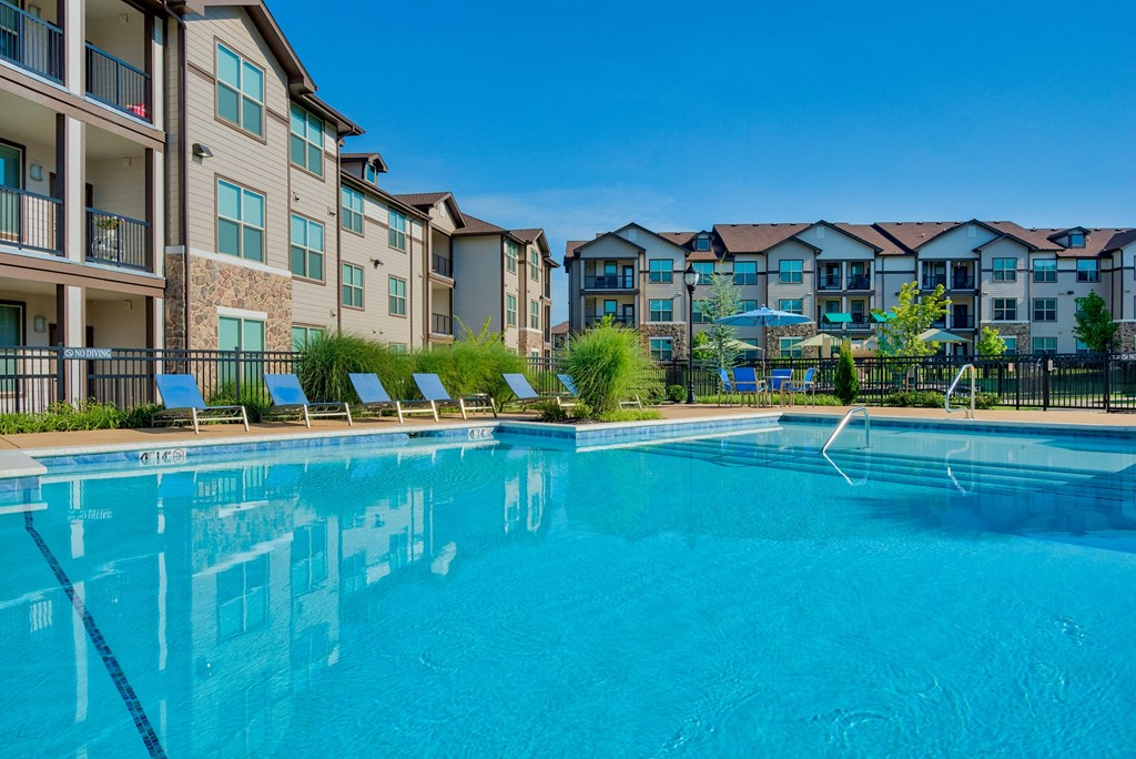 Pet-Friendly Rentals in Bentonville, AR – Parc at Bentonville – A large swimming pool with the apartments surrounding it and beach chairs