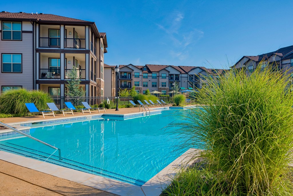 Pet-Friendly Rentals in Bentonville, AR – Parc at Bentonville – A large swimming pool with the apartments surrounding it and beach chairs