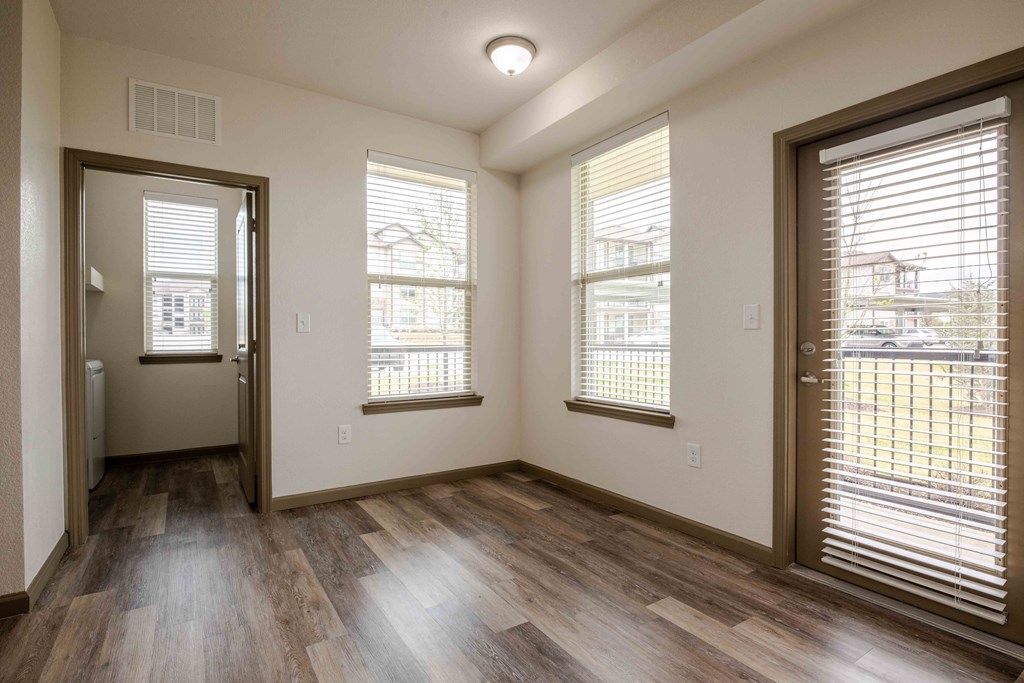 a living space with three windows and a door at Parc at Bentonville Apartments in Bentonville, AR