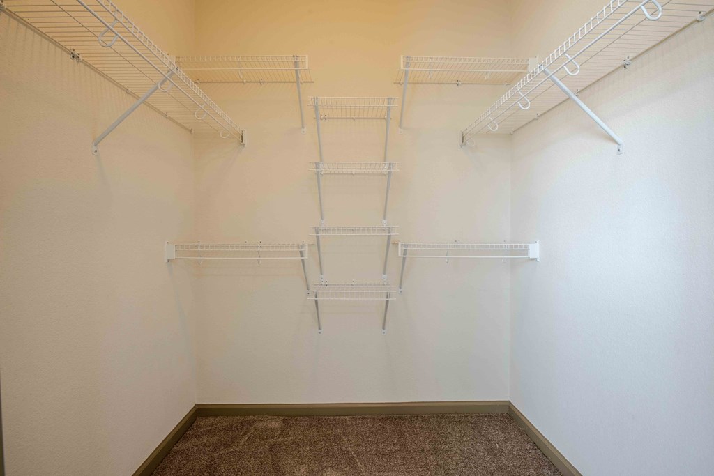 a walk in closet with white walls and shelves at Parc at Bentonville Apartments in Bentonville, AR