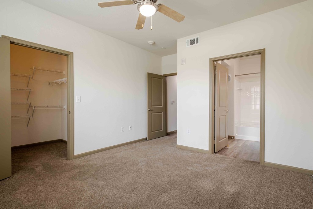 A bedroom with a ceiling fan and doors
