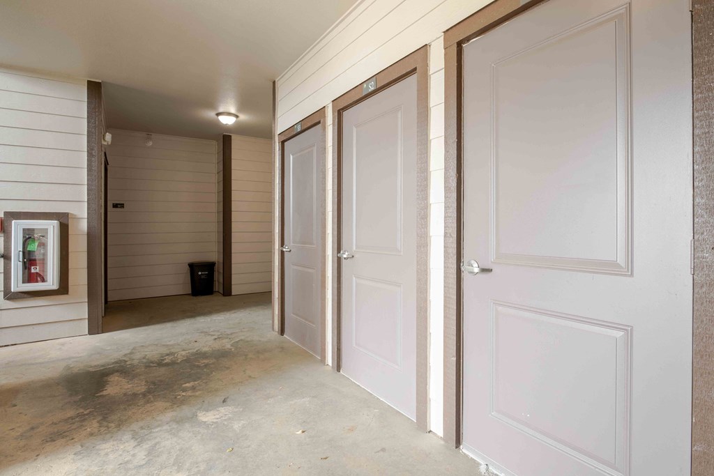 a row of doors in a hallway with a painting on the wall at Parc at Bentonville Apartments in Bentonville, AR