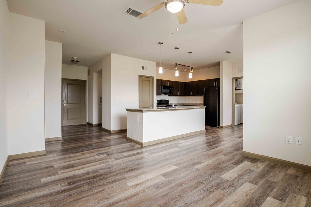 a kitchen and living room with white walls and wood floors and ceiling fan/light at Parc at Bentonville Apartments in Bentonville, AR