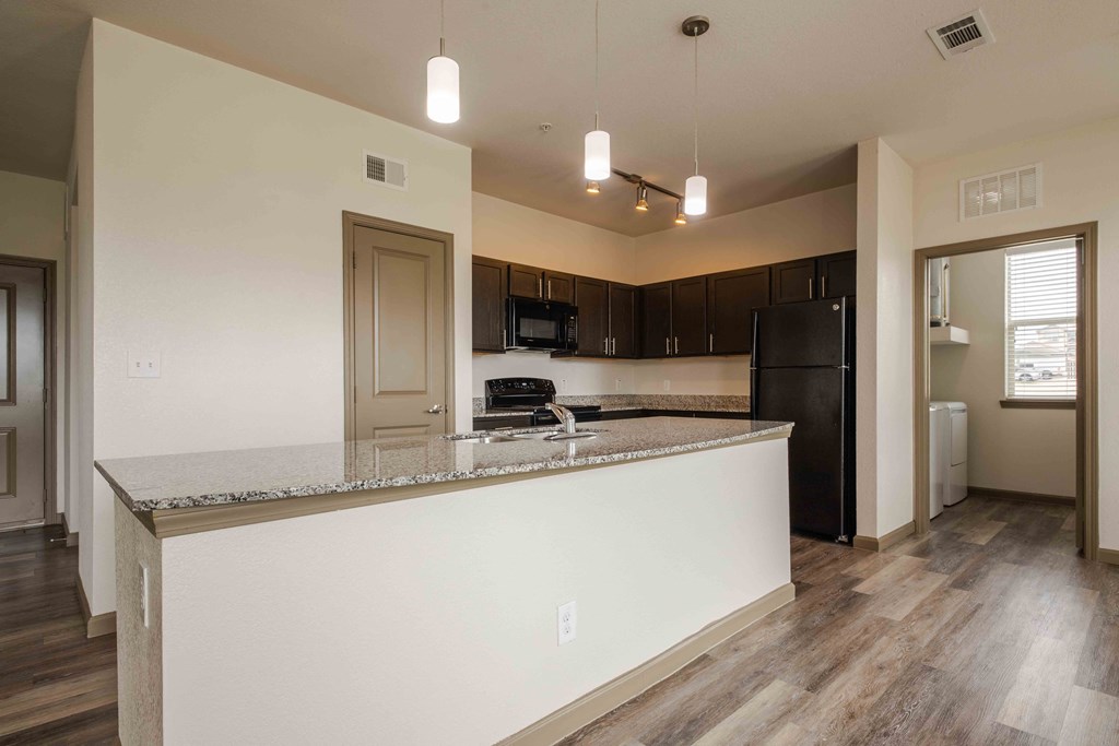 Open kitchen with wood flooring and island and sink and windows with blinds and ceiling fan