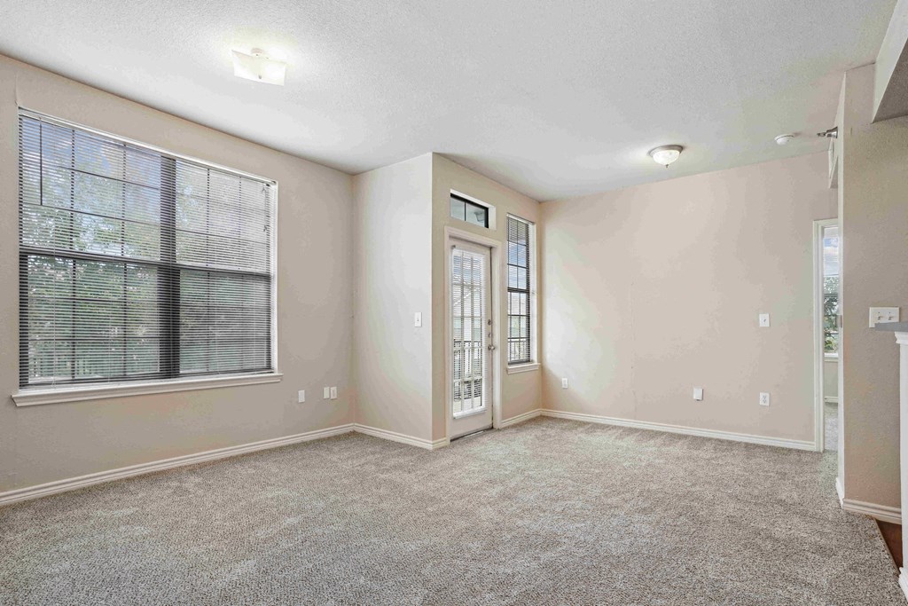 Pet-Friendly Rentals in Maumelle, AR – Parc at Maumelle – A room with a carpeted floor, a window with blinds, and a door with a window.