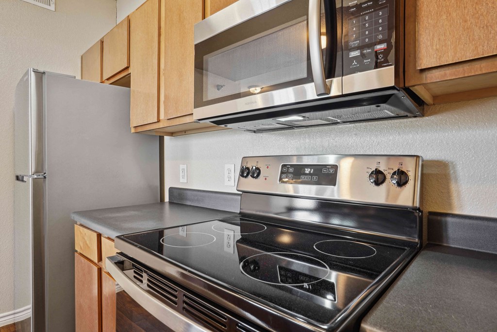 1, 2 & 3-Bedroom Apartments for Rent in Maumelle, AR – Parc at Maumelle – A modern kitchen with a stainless steel stove and microwave above it.