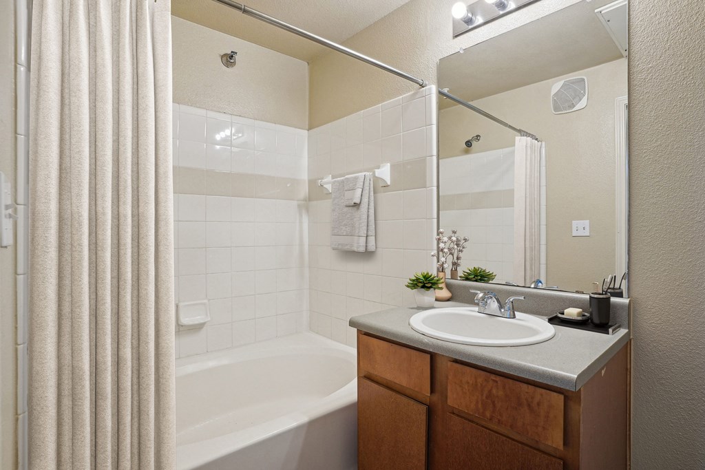 Apartments for Rent in Maumelle, AR 72113– Parc at Maumelle -   A bathroom with a white tub, sink, and a mirror.