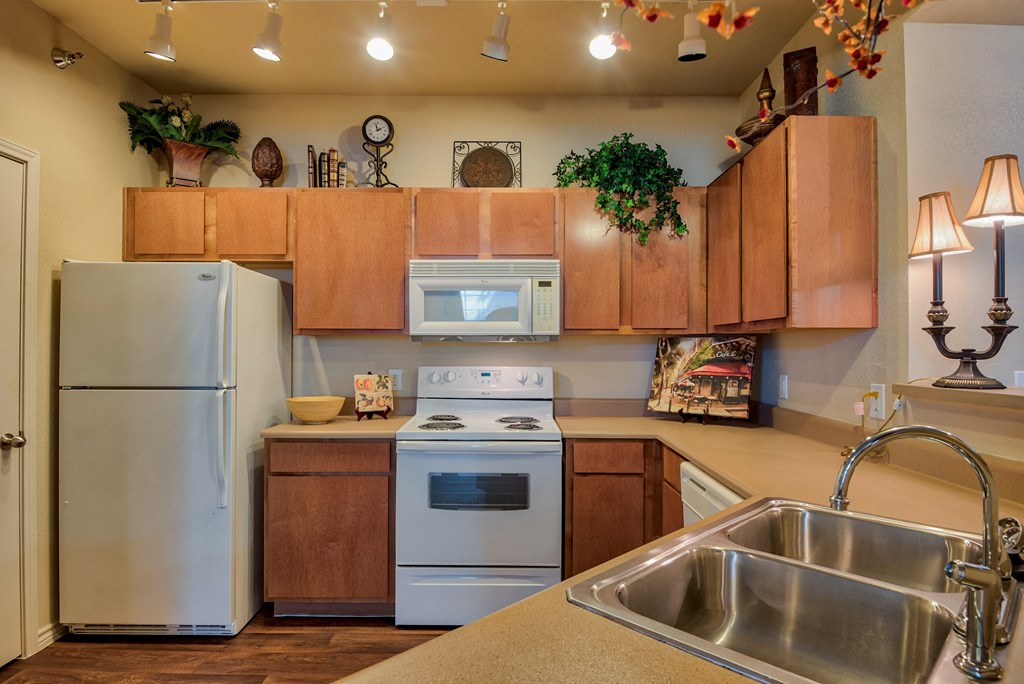 a kitchen with white appliances and wooden cabinets and steel sink and ceiling lights