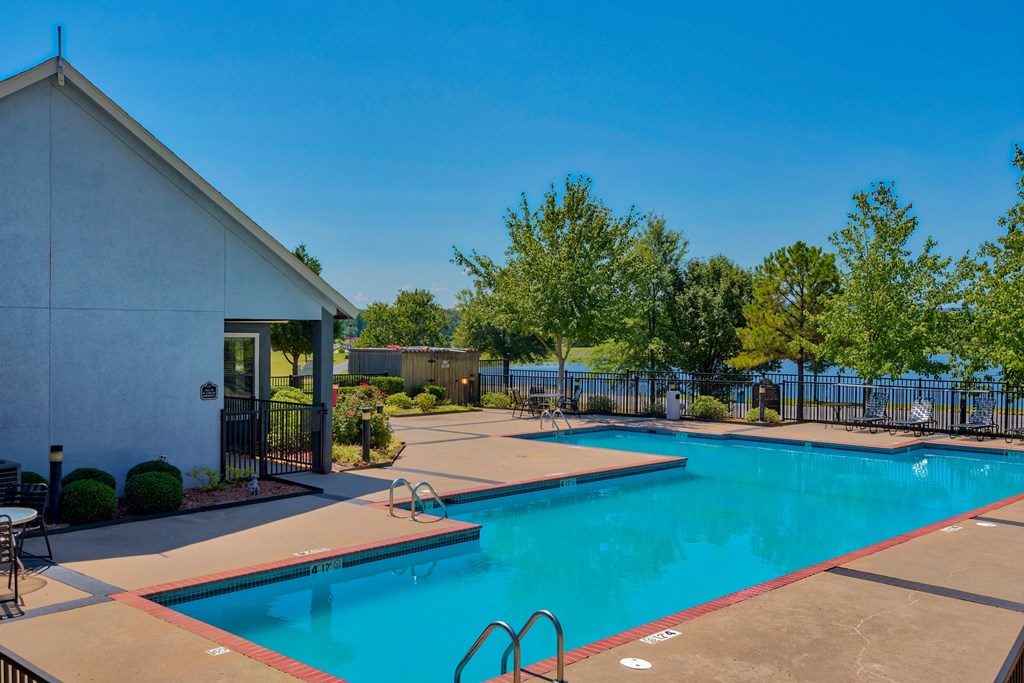 Apartments for Rent in Maumelle, AR 72113– Parc at Maumelle -   a swimming pool surrounded by trees and beach chairs