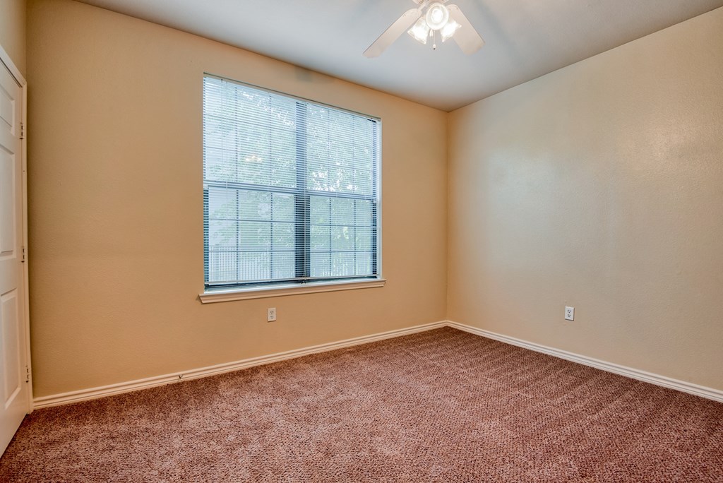 a bedroom with carpet and a large window and ceiling fan
