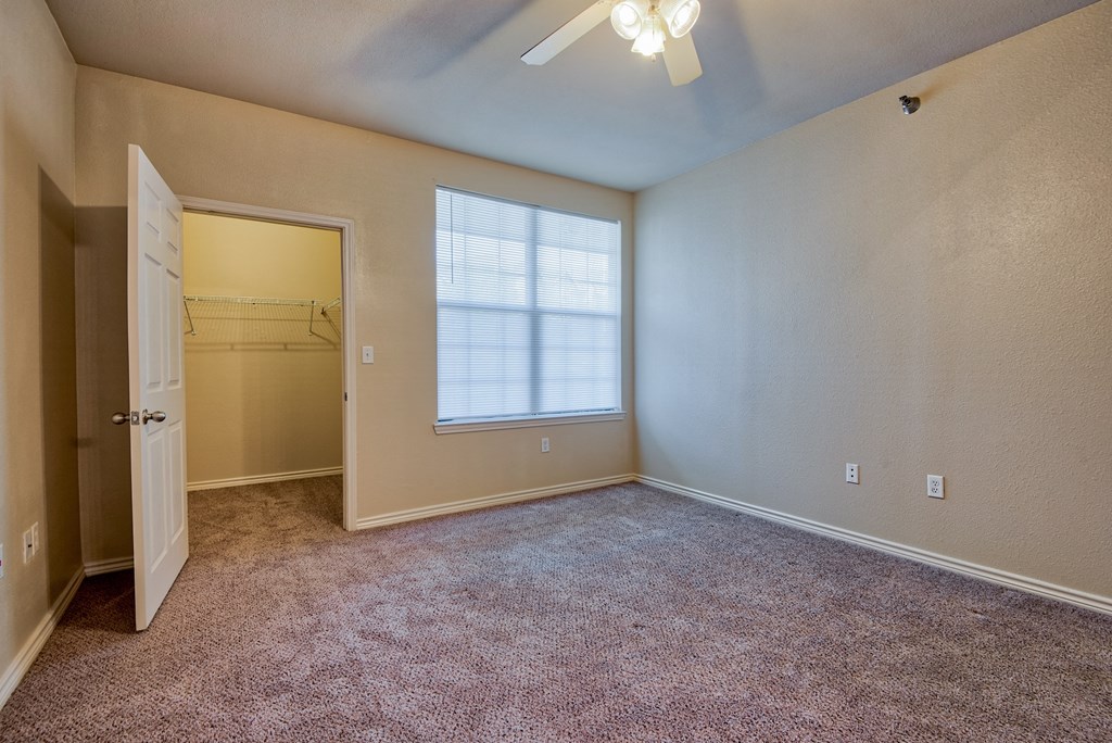 a bedroom with carpet and a large window and ceiling fan