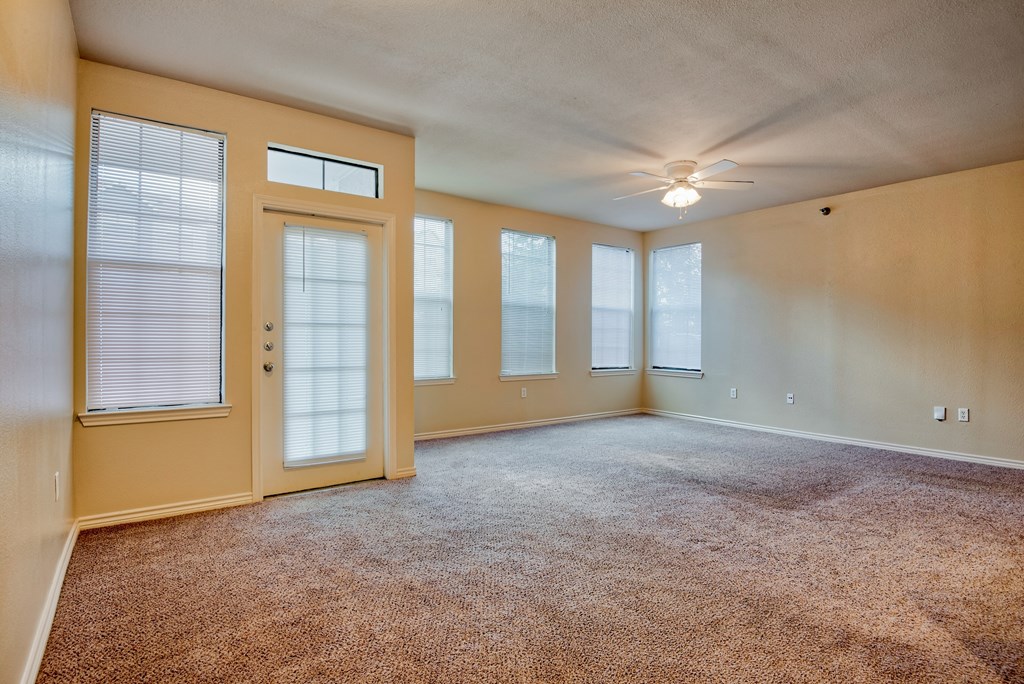 a living room with carpet and ceiling fan and windows with blinds