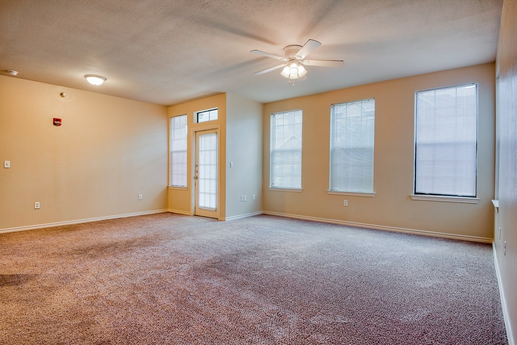 a living room with carpet and ceiling fan and windows with blinds