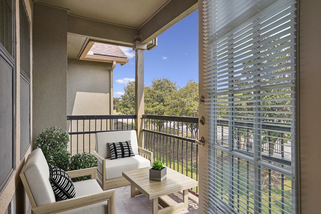 Pet-Friendly Rentals in Rogers, AR – Parc at Rogers – A patio with a white chair and a small table with a plant on it.