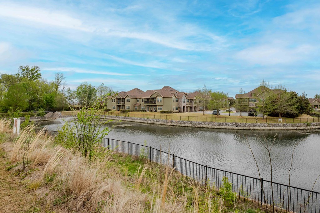 Pet-Friendly Rentals in Rogers, AR – Parc at Rogers –exterior building with a pond in front surrounded by a gate
