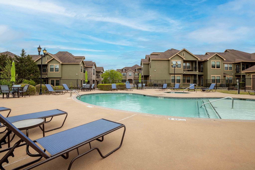Apartments for Rent in Rogers, AR 72758– Parc at Rogers-   Swimming pool surrounded by apartments and beach chairs