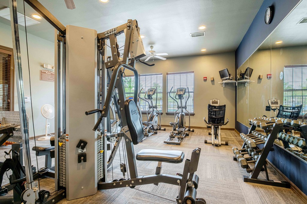 1, 2 & 3-Bedroom Apartments for Rent in Rogers, AR – Parc at Rogers– gym with lifting and cardio equipment with a big mirror and windows
