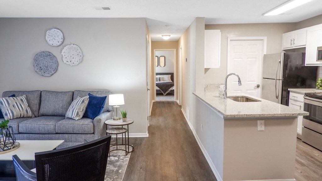 1 Park Central Apartments, Peachtree Corners, Georgia a living room with a couch a table and a kitchen with a sink