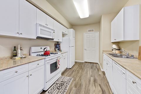 a spacious kitchen with white cabinets and appliances and a sink