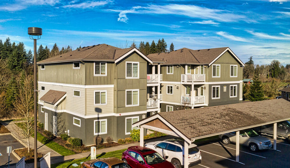 a large apartment building with cars parked in a parking lot