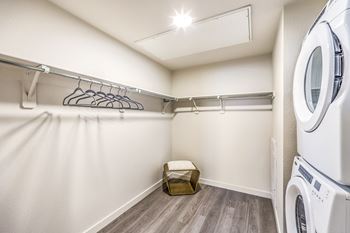 a washer and dryer in a laundry room with white walls and wood floors