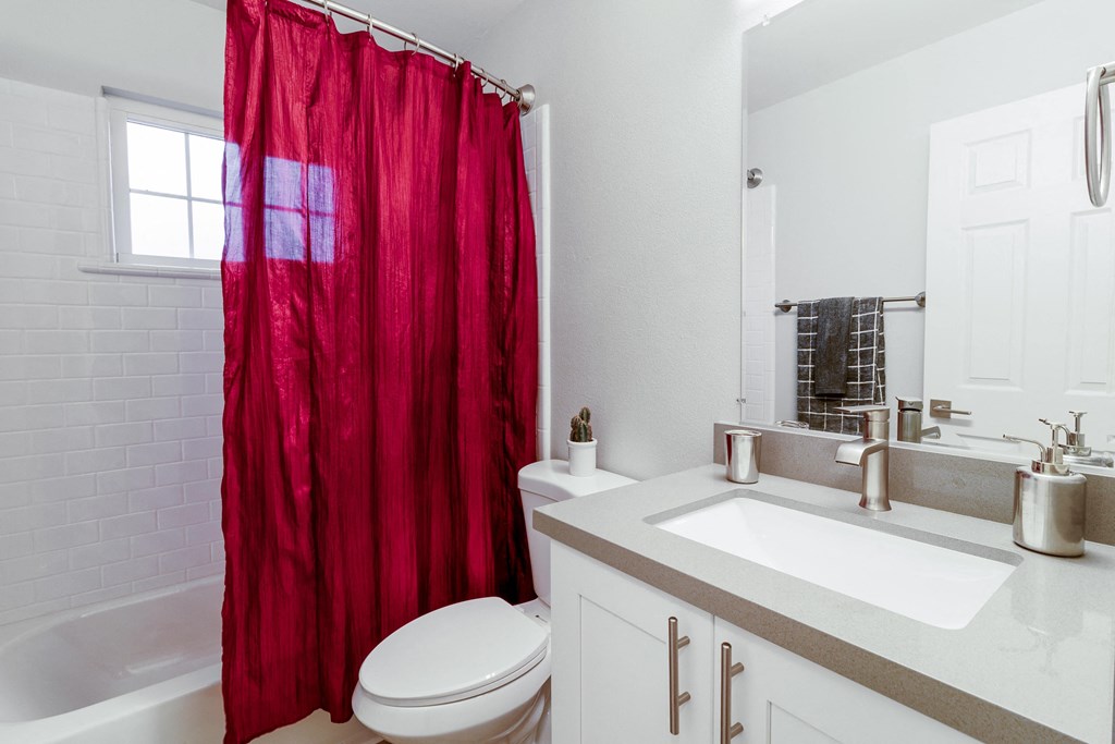 a bathroom with a red shower curtain and a toilet and sink