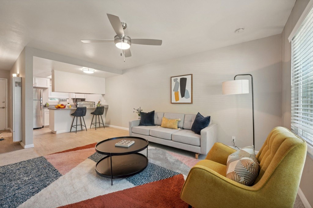 a living room with a couch and a chair and a ceiling fan
