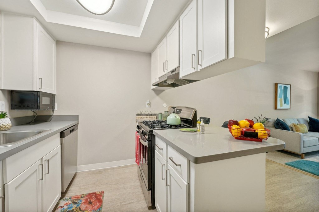 a renovated kitchen with white cabinets and appliances and a living room with a couch