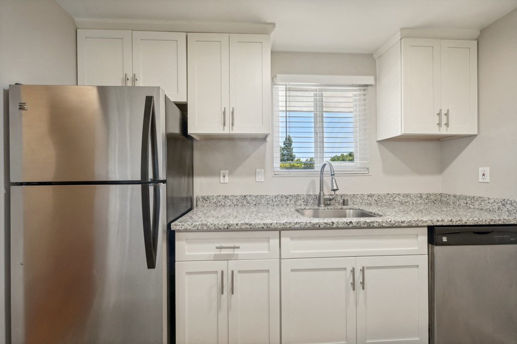 a kitchen with white cabinets and a stainless steel refrigerator