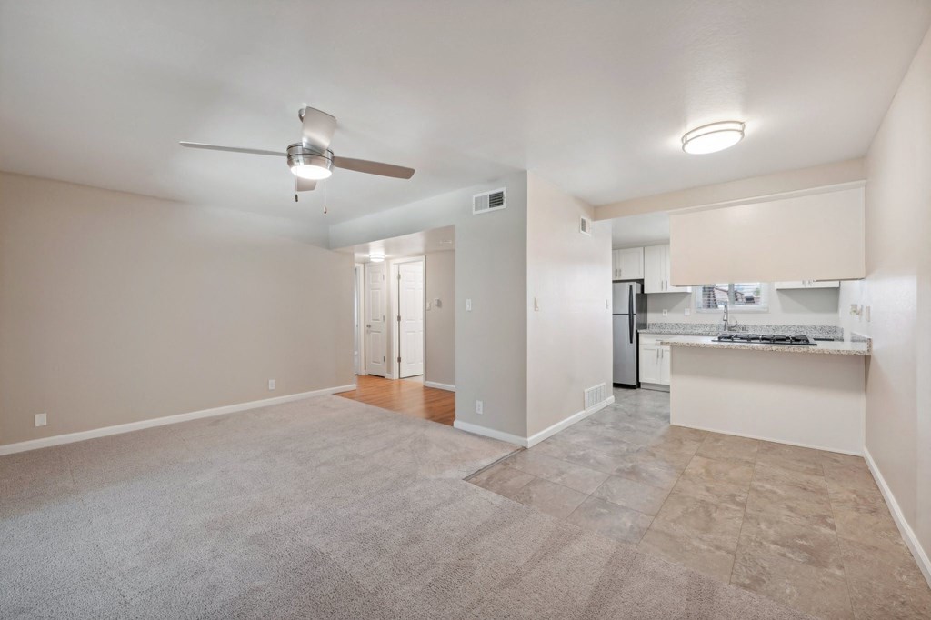 an empty living room and kitchen with a ceiling fan