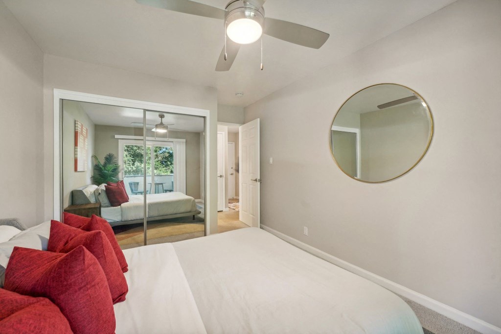 a bedroom with a white bed and a ceiling fan