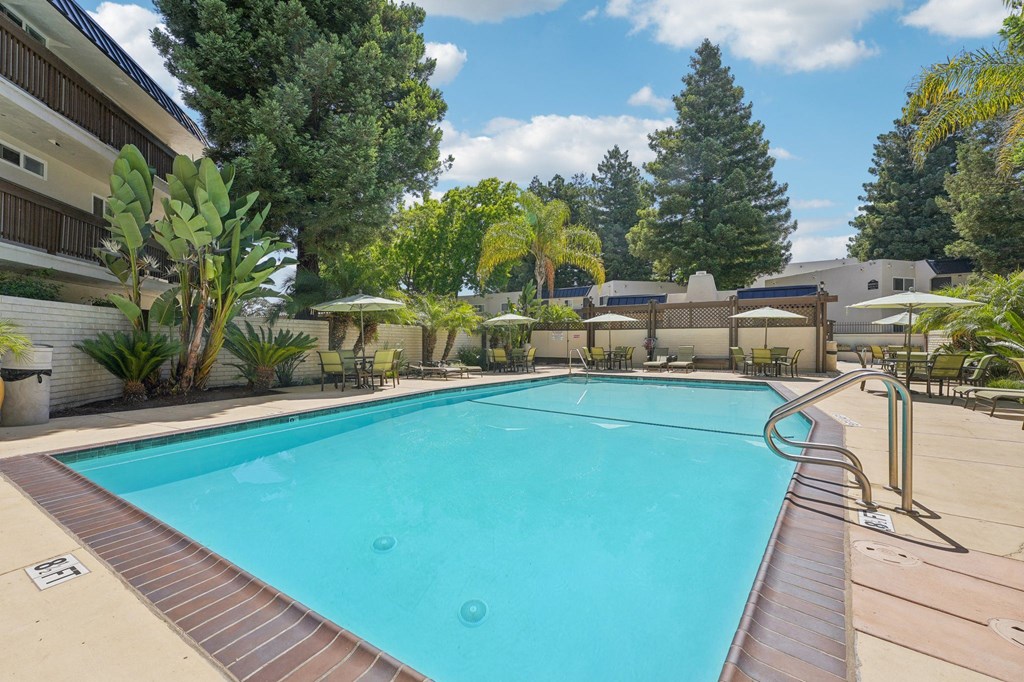 a swimming pool with trees and a building in the background