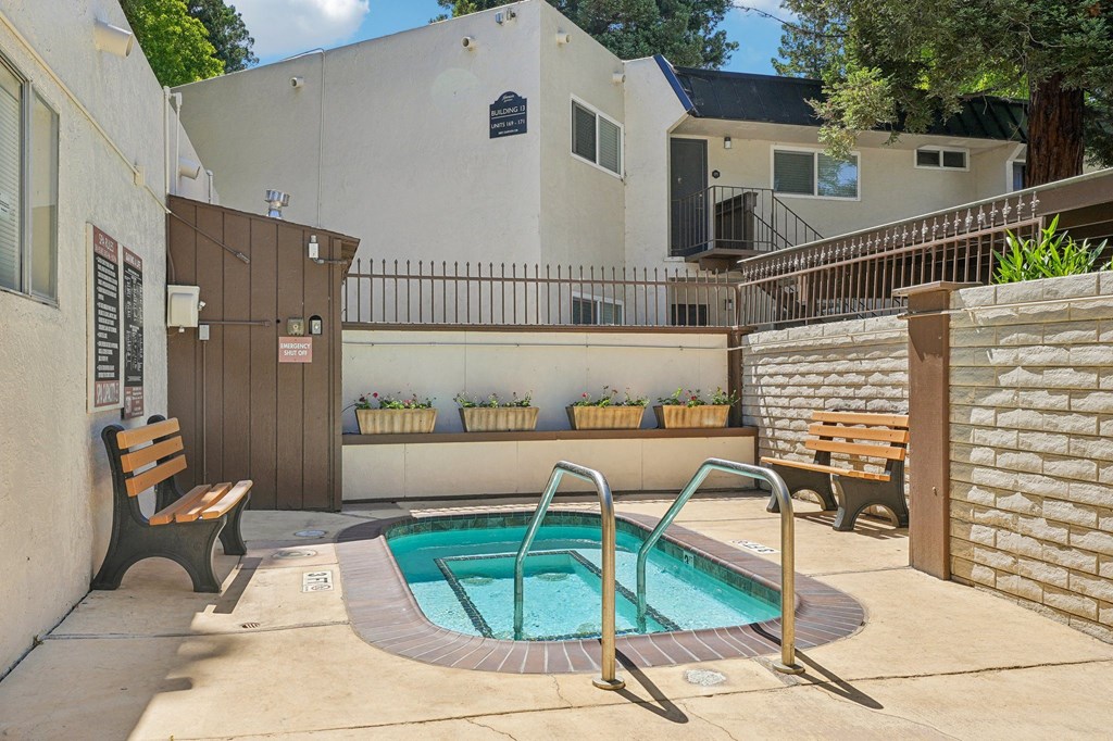 the pool is in the backyard of a house with a hot tub